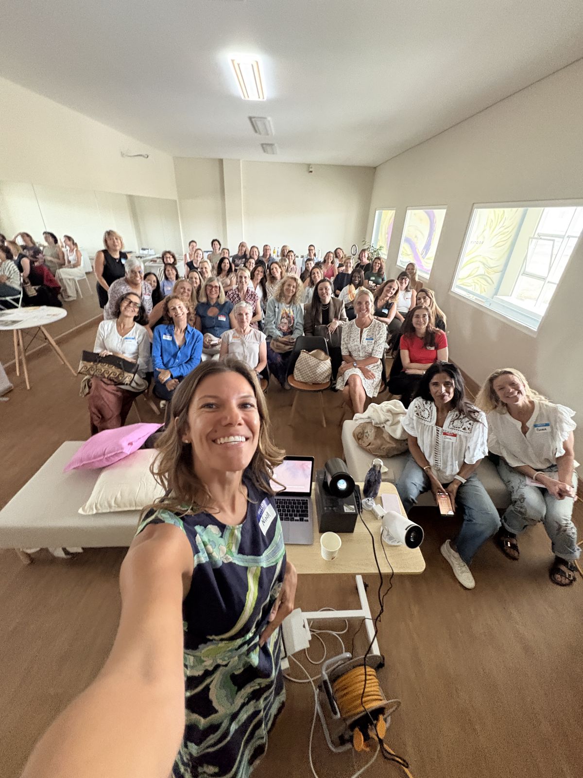 Nina taking a selfie with a full hall of women behind her